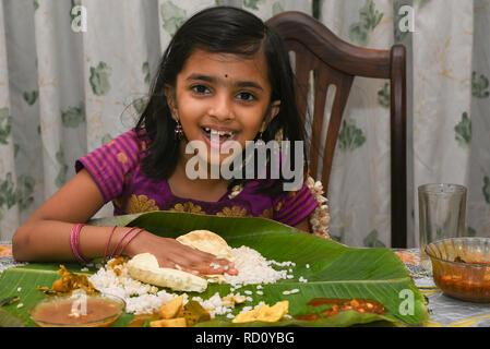 Indian girl enfant manger Onam Sadhya grand fête servi sur des feuilles de banane avec la main sur l'ONAM, Vishu Harvest Festival du Kerala, en Inde. Banque D'Images