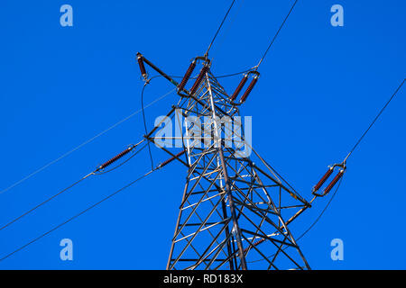 Ligne de transmission à haute tension soutenue par la construction métallique d'un poteau électrique à haute tension avec les isolateurs et les connecteurs de puissance sur un fond bleu Banque D'Images
