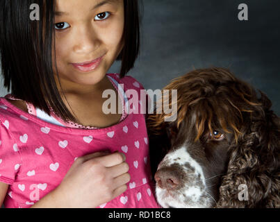 Enfant et chien : fille avec son animal préféré photographiés en studio Banque D'Images