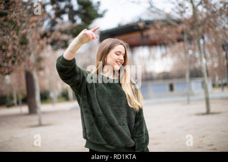 Happy young woman jumping et profiter avec bras blessé dans le parc Banque D'Images