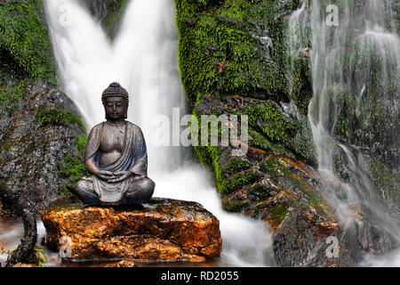 Statue de Bouddha assis en face d'une cascade Banque D'Images