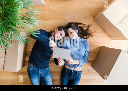 Une vue du dessus du jeune couple avec tablet et boîtes de carton déménagement dans une nouvelle maison. Banque D'Images