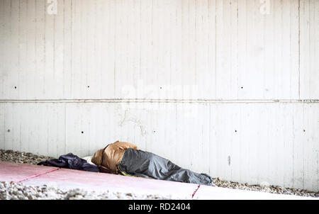 Une vue arrière du sans-abri mendiant l'homme allongé sur le sol à l'extérieur en ville, dormir. Banque D'Images