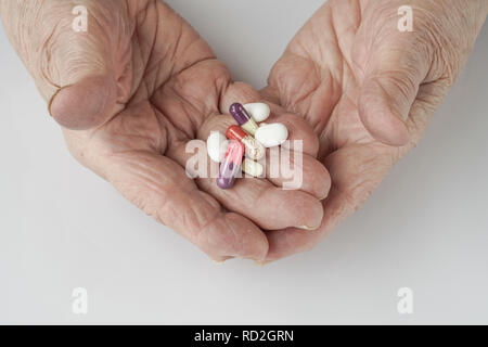 Holding pills sur palm d'une personne senior on white Banque D'Images