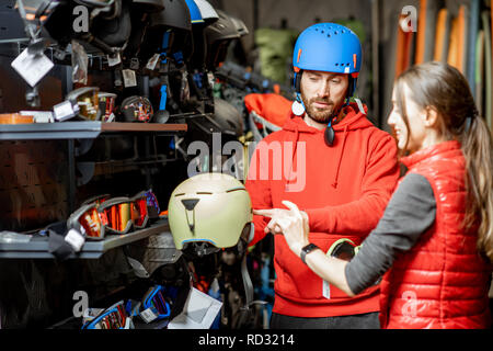 L'homme et de la femme le choix de casque de protection pour l'équitation ou la randonnée dans la boutique avec des produits de sport Banque D'Images