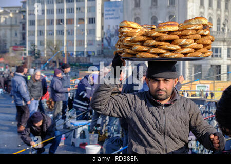 Istanbul, Turquie : Man selling simit (pain traditionnel turc ronde) pour le pêcheur sur le pont de Galata. Portrait avec le vendeur l'exécution simit on head Banque D'Images