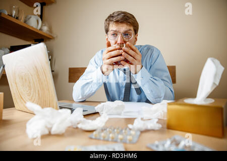 Se sentir malade et fatigué. L'homme avec une tasse de thé chaud working in office, homme d'affaires pris froid, la grippe saisonnière. La pandémie de grippe, la prévention des maladies, la climatisation au pouvoir provoquer la maladie Banque D'Images