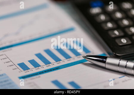 Les graphiques et tableaux, calculatrice et stylo sur allongé sur table en bois Banque D'Images