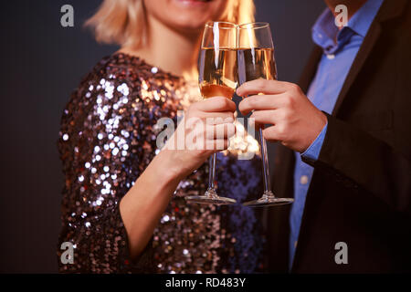 Photo de couple avec verres de champagne avec champagne sur fond noir Banque D'Images