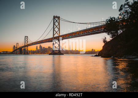 Classic vue panoramique de San Francisco skyline avec célèbre Oakland Bay Bridge illuminée en magnifique lumière du soir au coucher du soleil en été Banque D'Images