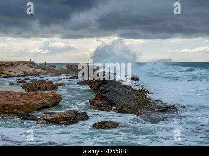 Mer grosse batter le littoral de la côte d'Agios Georgios à Chypre, avec la petite île de Yeronisos derrière. Banque D'Images