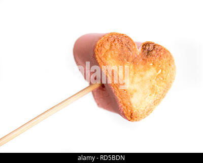 Forme coeur grillé sur une brochette de guimauves dans femme Main sur fond blanc. Banque D'Images