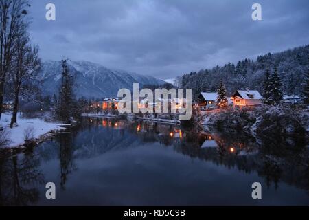 Petites maisons couvertes de neige et feux d'chtistmas dans le pittoresque Bad Goisern, Hallstatt. La tombée de la vue depuis la rivière. Banque D'Images