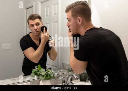 Bon Jeune homme lave les mains et le visage dans la salle de bains lavabo et miroir Accueil Obtenir propre et soigné au cours de la routine du matin Banque D'Images