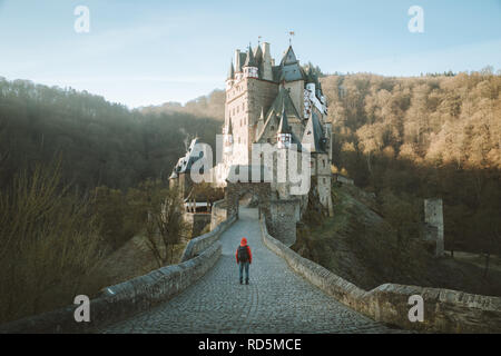 Vue panoramique de young explorer avec sac à dos en admirant la vue au célèbre château d'Eltz au lever du soleil à l'automne, Rheinland-Pfalz, Allemagne Banque D'Images