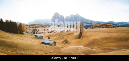 Belle vue sur la montagne chalets traditionnels en bois sur Scenic Alpe di Siusi célèbre Langkofel avec des pics de montagne dans l'arrière-plan dans la matinée d'or Banque D'Images