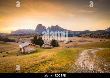 Belle vue sur la montagne chalets traditionnels en bois sur Scenic Alpe di Siusi célèbre Langkofel avec des pics de montagne dans l'arrière-plan dans la matinée d'or Banque D'Images