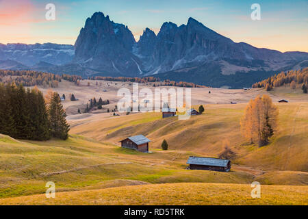 Belle vue sur la montagne chalets traditionnels en bois sur Scenic Alpe di Siusi célèbre Langkofel avec des pics de montagne dans l'arrière-plan dans la matinée d'or Banque D'Images