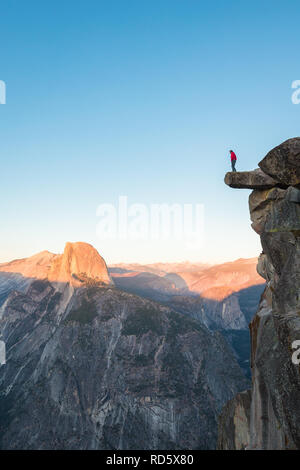 L'intrépide randonneur est debout sur un rocher en surplomb en profitant de la vue vers célèbre Demi Dôme à Glacier Point oublier dans beau crépuscule du soir