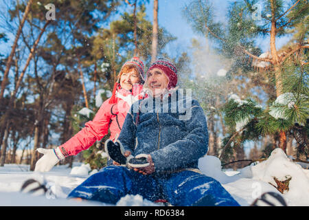 Senior couple hugging in winter forest. L'homme et la femme assis dans la neige et s'amuser le jour de la Saint-Valentin à l'extérieur Banque D'Images