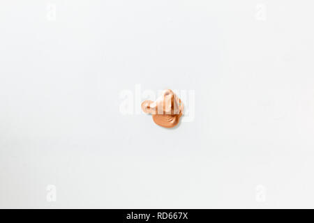Petit blob beige du maquillage au centre d'un fond blanc. Banque D'Images