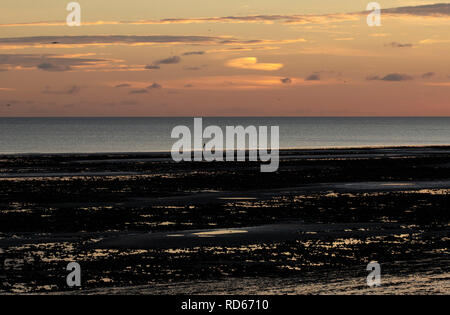 Personne seule en silhouette sur une plage au coucher du soleil Banque D'Images