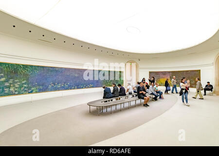 Les personnes qui regardent les lilas d'eau de Claude Monet sont établies dans des panneaux incurvés dans une salle ovale à l'Orangerie ou au Musée de l'Orangerie, Paris, France Banque D'Images