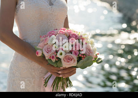 Mariée est titulaire d'un bouquet de mariage rose et blanc sur le fond de la mer Banque D'Images