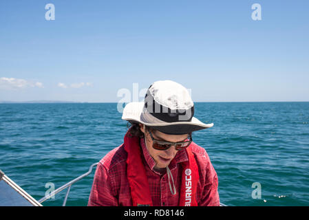 L'homme à chapeau et un verre au soleil sur le bateau de pêche avec gilet Banque D'Images