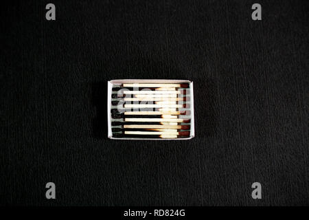 Allumettes brûlées avec tête rouge dans la boîte d'allumette. Isolé sur le fond noir. Banque D'Images