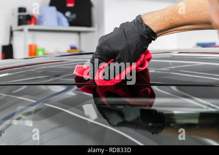 Un homme en voiture de nettoyage avec chiffon microfibre. Concept d'esthétique automobile. Esthétique auto. Le nettoyage à l'éponge. Des voitures de nettoyage avec microfibre. Solution pour Banque D'Images