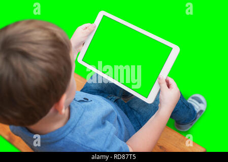 Garçon jouer jeu ou regarder des vidéos sur comprimé blanc. Fond écran isolé et en vert, chroma key. Banque D'Images