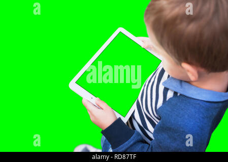 Garçon jouer jeu sur tablette blanche. Fond écran isolé et en vert, chroma key. Banque D'Images