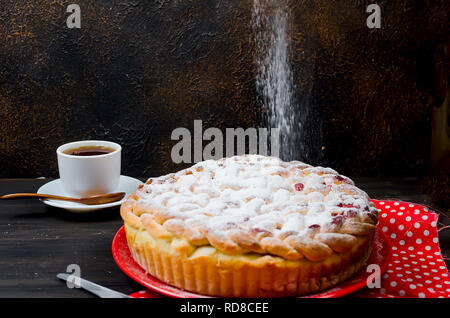 Délicieux petit cherry Pie saupoudrés de sucre glace sur la plaque sur la vieille table en bois sombre. Tarte aux cerises, série de décisions Banque D'Images