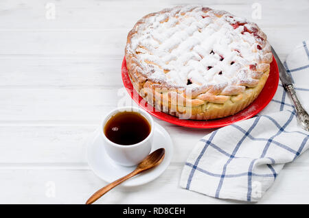 Délicieux petit cherry Pie saupoudrés de sucre glace sur la plaque whits tasse de thé sur la vieille table en bois blanc. Tarte aux cerises, série de décisions Banque D'Images