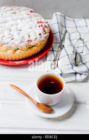 Délicieux petit cherry Pie saupoudrés de sucre glace sur la plaque whits tasse de thé sur la vieille table en bois blanc. Tarte aux cerises, série de décisions Banque D'Images