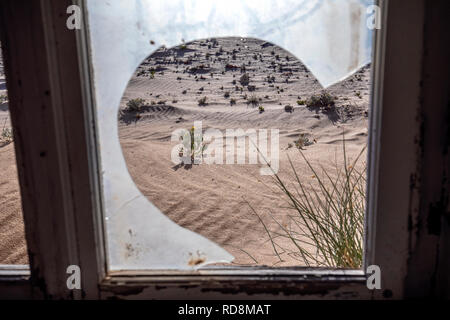 Vue à travers la fenêtre de verre cassée à Kolmanskop Ghost Town - Luderitz, Namibie, Afrique Banque D'Images