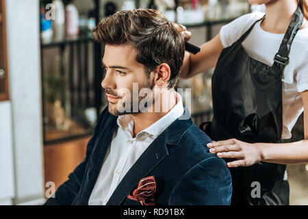 Cropped shot of hairstylist peigner les cheveux de beau jeune homme en instituts de beauté Banque D'Images