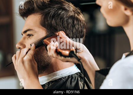 Cropped shot of hairstylist holding et peigne les cheveux de fraisage à beau client Banque D'Images