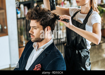 Cropped shot of young hairdresser combing et séchage des cheveux à beau client en instituts de beauté Banque D'Images