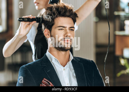 Cropped shot of hairstylist peigner et sécher les cheveux pour beau jeune homme en instituts de beauté Banque D'Images