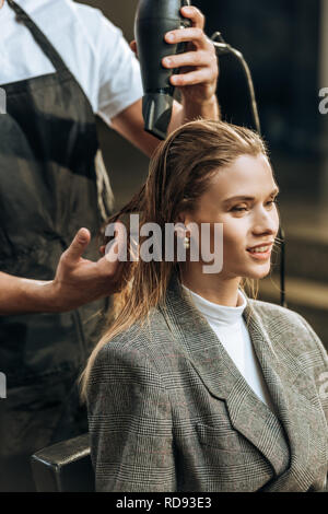 Cropped shot de coiffeur pour cheveux séchage beautiful smiling girl in salon de Banque D'Images