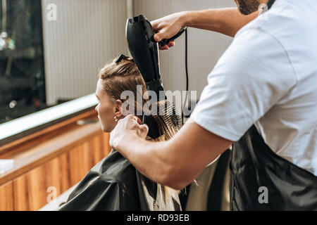 Cropped shot de coiffure cheveux séchage à attractive young woman in salon de Banque D'Images