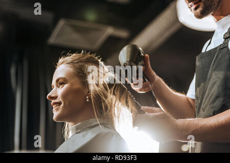 Low angle view of hairstylist peigner et sécher les cheveux pour belle jeune femme en instituts de beauté Banque D'Images