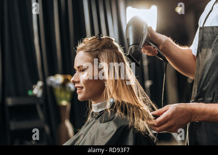 Cropped shot of hairstylist peigner et sécher les cheveux pour belle jeune femme en instituts de beauté Banque D'Images