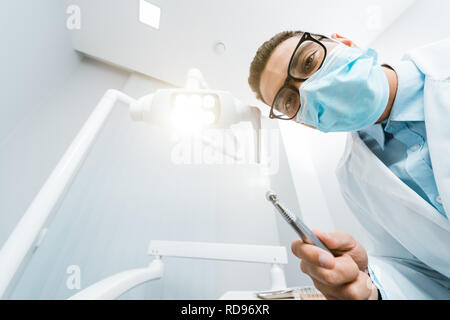 African American dentiste en blouse blanche et masque à percer dans la main Banque D'Images