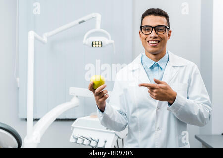 Handsome african american doctor dans les verres pointant chez apple Banque D'Images