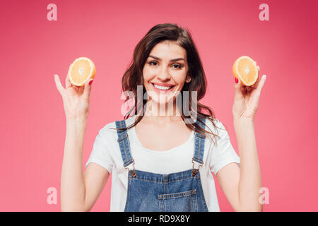 Attractive Woman holding orange en mains isolé sur pink Banque D'Images