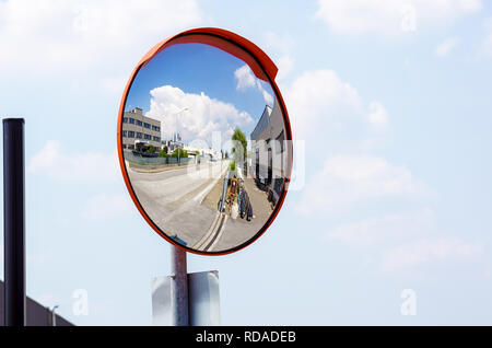 Miroir convexe d'extérieur coffre accroché sur mur avec la réflexion d'un point de vue des routes urbaines de voitures stationnées le long de la rue par des immeubles d'habitation. Banque D'Images