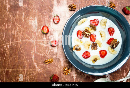 Bouillie de semoule avec des fraises et des écrous. Sur fond rustique. Banque D'Images